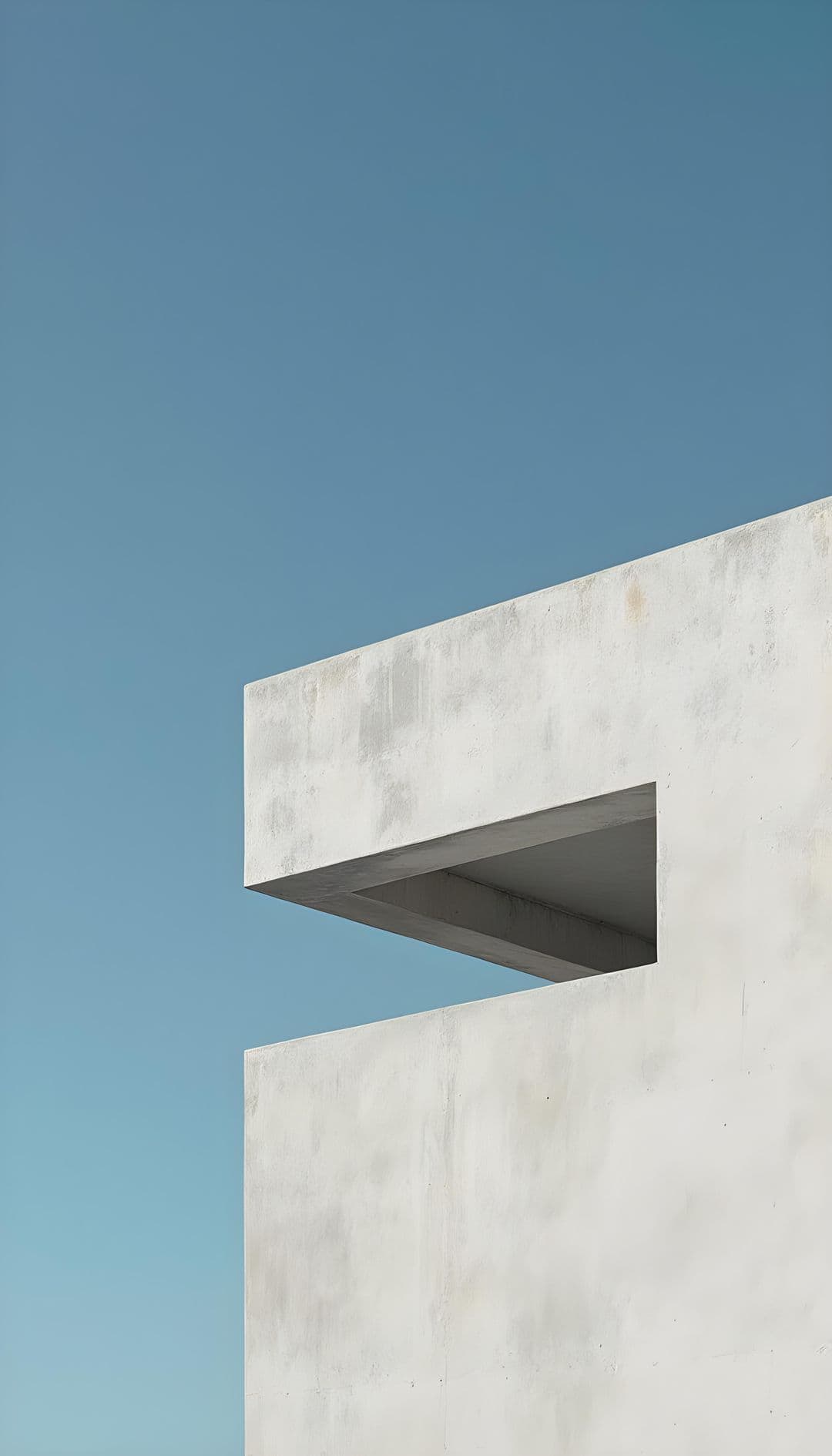 White minimalist building with sharp geometric lines against a blue sky