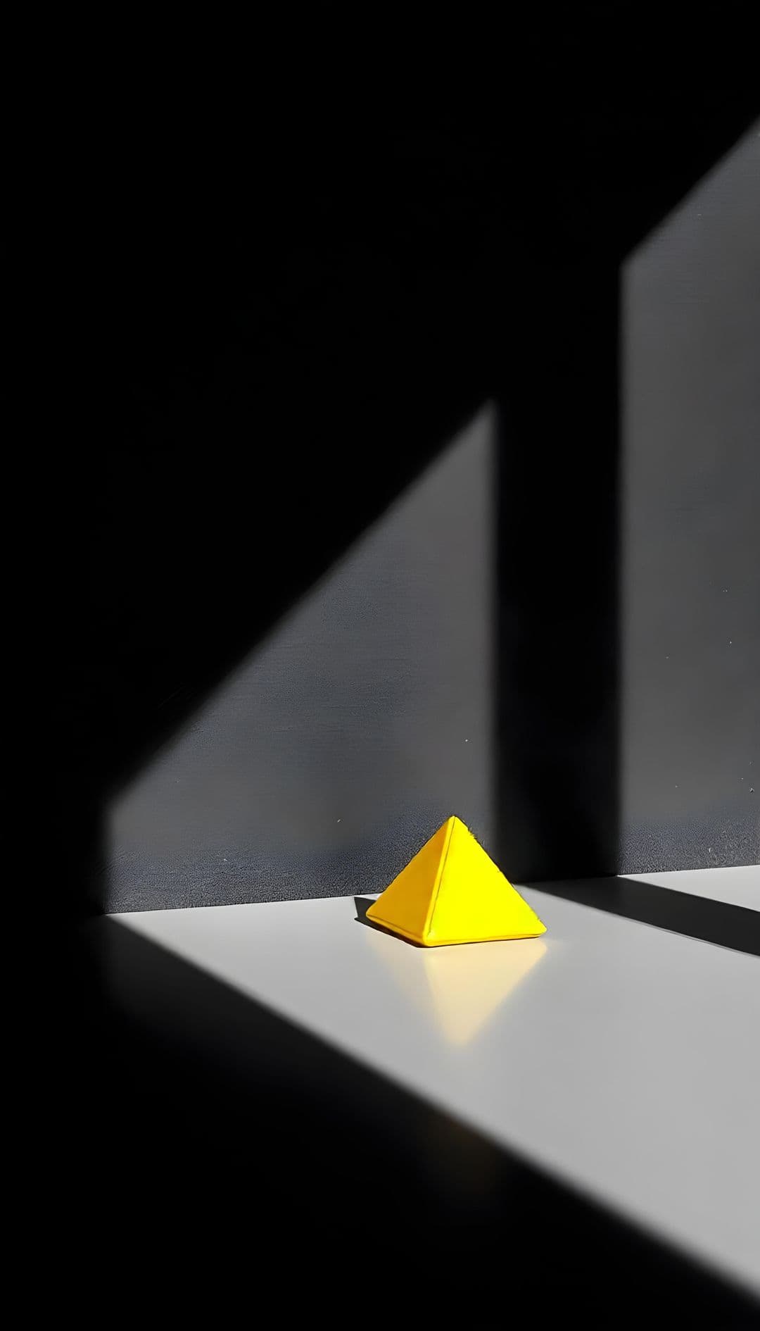A yellow pyramid on a reflective surface with dramatic lighting.