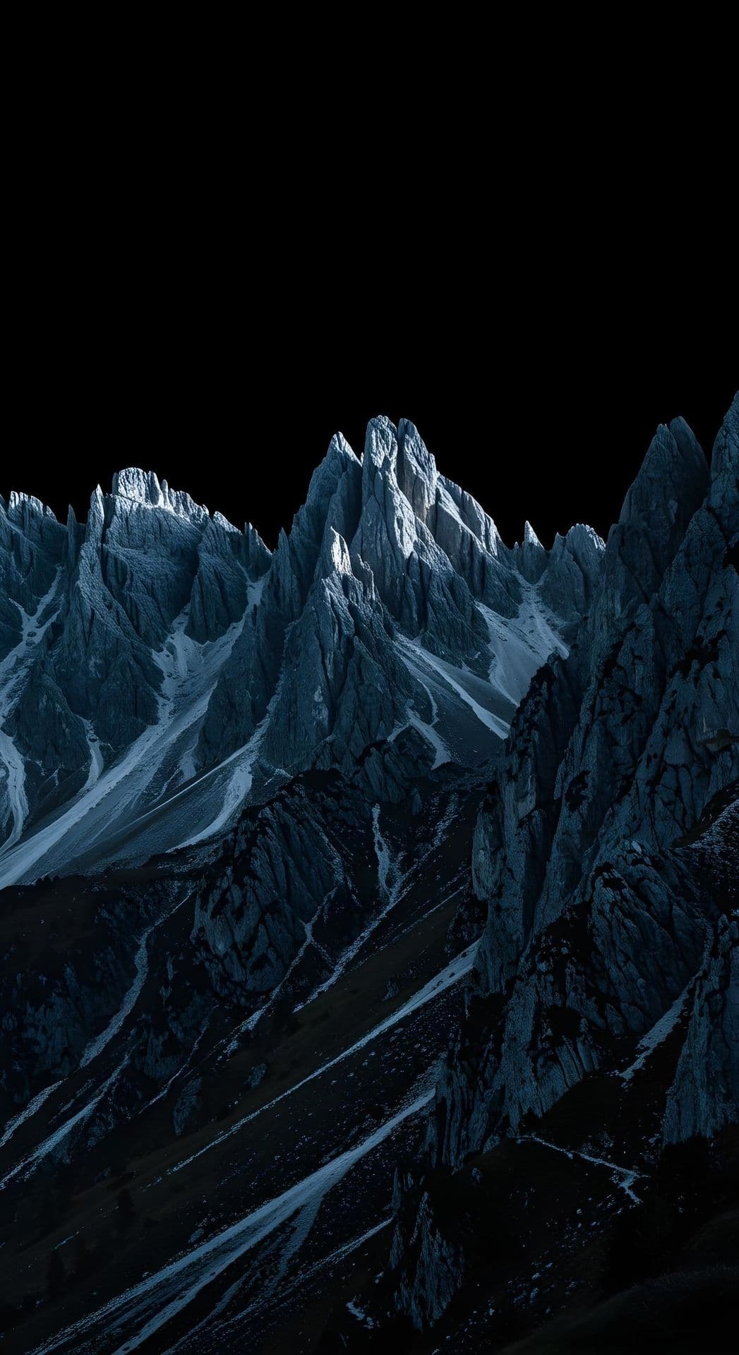 A mountain range with peaks lit by moonlight against a dark sky.