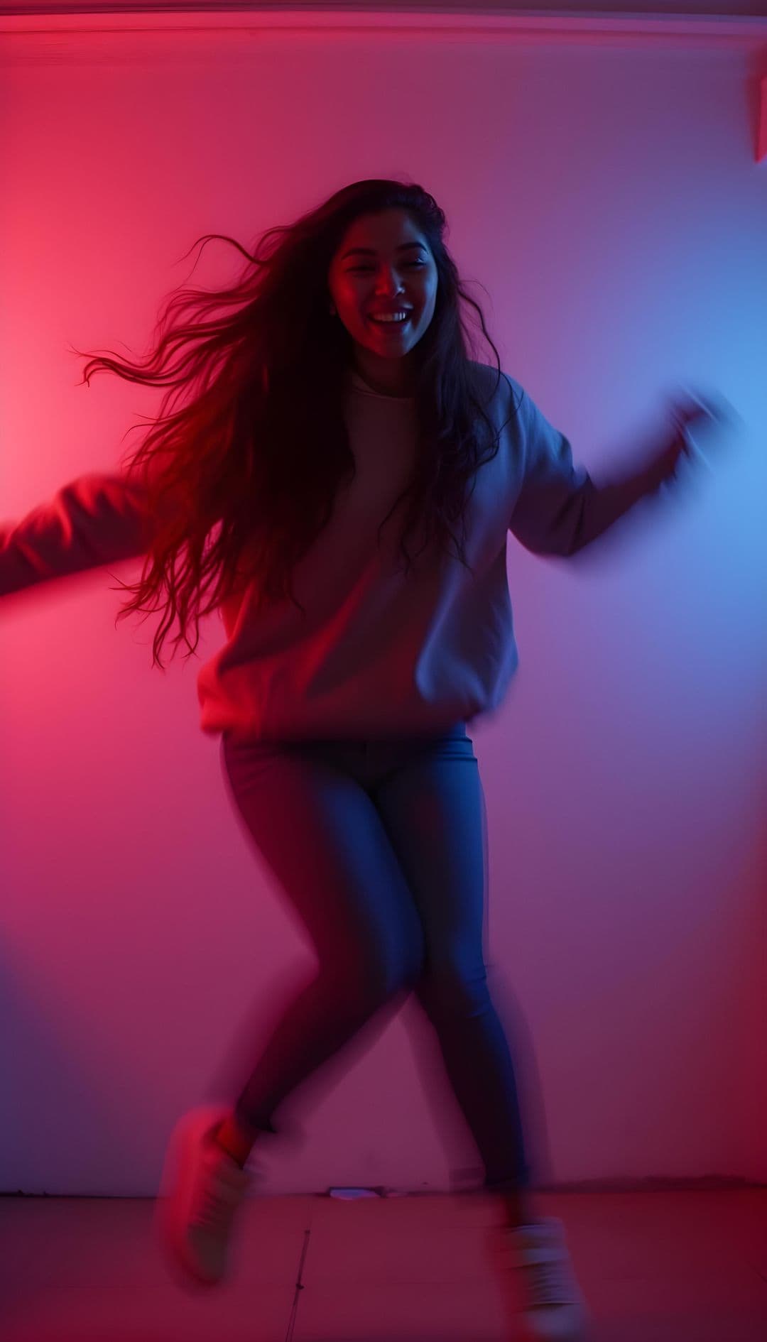 A person jumping in a minimalist room with red and blue lights.